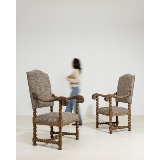 A striking pair of 19th century oak armchairs inspired by medieval “castle” seating, featuring high backs and strong...