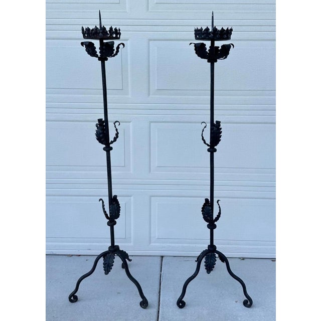 A pair of mid-20th century Spanish hand-forged black iron floor candlesticks, Torchieres each standing 60 inches high...