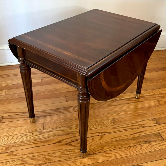 Drop-leaf side table with beautiful inlay detailing, after Baker Furniture. Feet are capped with brass, and table leaves...