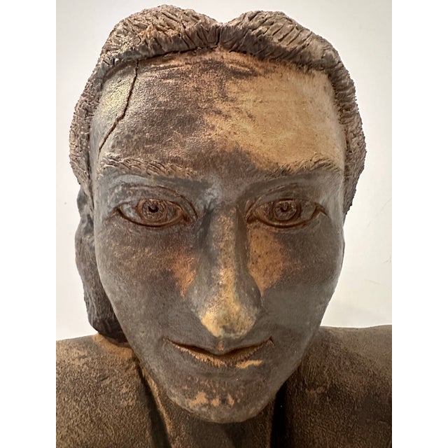This ceramic bust presents a contemplative female figure rendered with subtle realism and earthy texture. The sculptor’s...