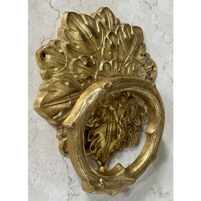 Vintage brass doorknocker featuring decorative leaf and twig design. Holes for hanging. Hardware not included. Lovely patina.