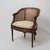 Elegant Louis XVI style neoclassical cane barrel chair, dating to circa 1920. This refined bergère features a shaped cane...
