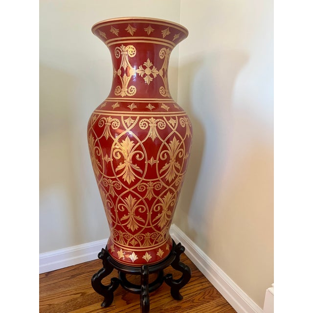 Beautiful oversized decorative floor vase featuring a rich deep red finish with intricate gold detailing throughout. The...