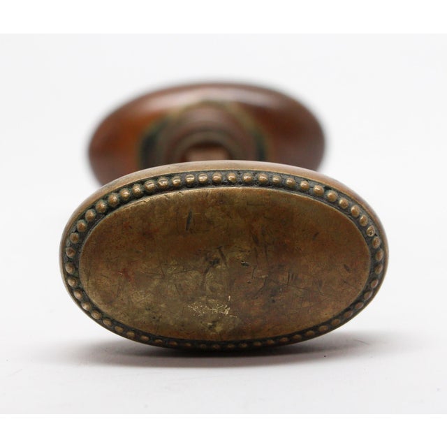 Beaded oval brass door knobs with an antique patina. The manufacturer and date of creation is unknown. Knobs take a 0.375...
