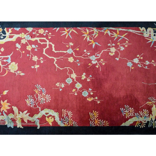 A beautiful early 20th century Chinese Art Deco rug with a deep cranberry colored background surrounded by a black border,...