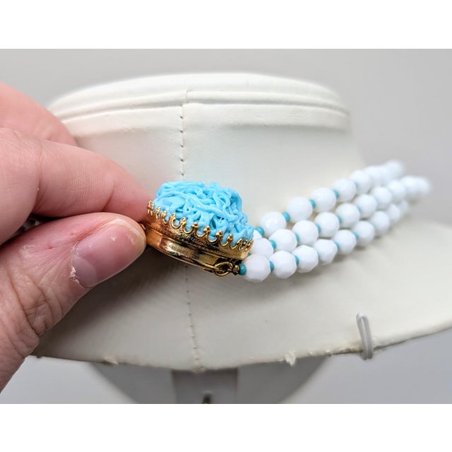 1960s 3-strand goldtone faceted white resin beads with an round domed art glass faux-turquoise box clasp. Marked "Hattie ©...