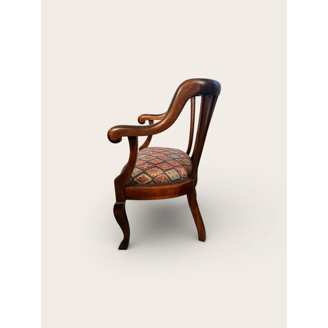 A refined Empire-style scroll armchair crafted in richly patinated mahogany, executed in the fashion of Mueller. The chair...