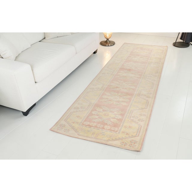 This is a vintage Turkish Oushak rug from the Mid 20th Century. The piece was hand-knotted.