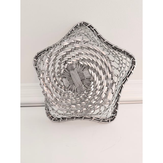 Handwoven sculptural metal basket with an airy openwork design and softly organic silhouette. Finished in a muted silver...