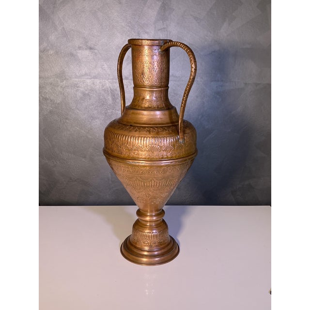 A highly decorated, chiseled and embossed two-handled copper amphora, likely Middle Eastern, from the 19th-20th century....