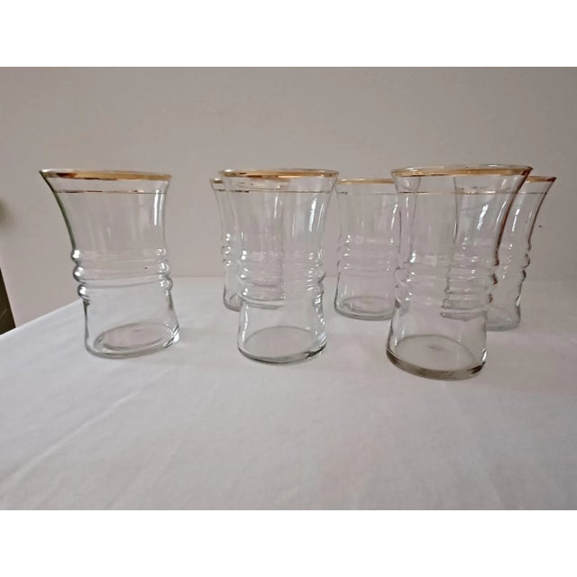 Fun mid-century modern tumblers have a flared gold rim and send gold pinstripe below. The ribbed center of the tumbler...