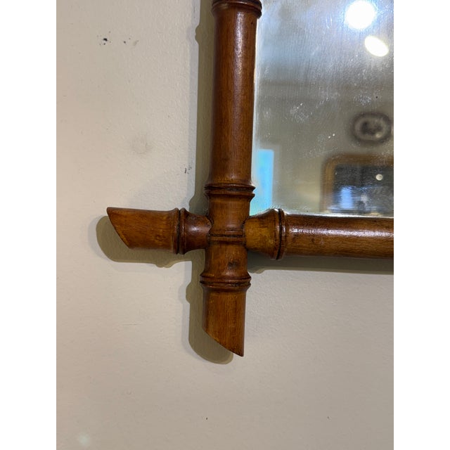 This is a French antique faux-bamboo wall mirror with a hand-carved wood frame. The frame is wood that has been shaped and...