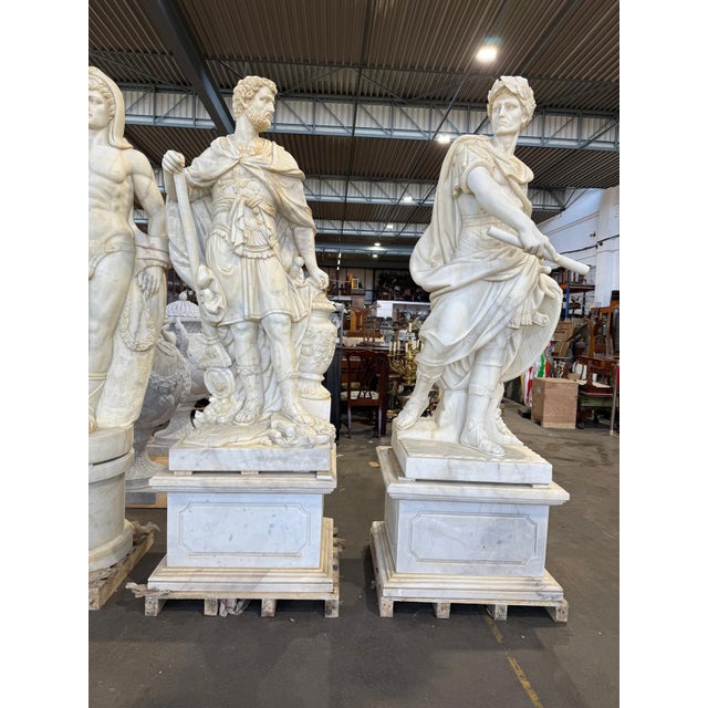 An impressive pair of monumental carved marble figures in the classical tradition, depicting idealized warrior figures...