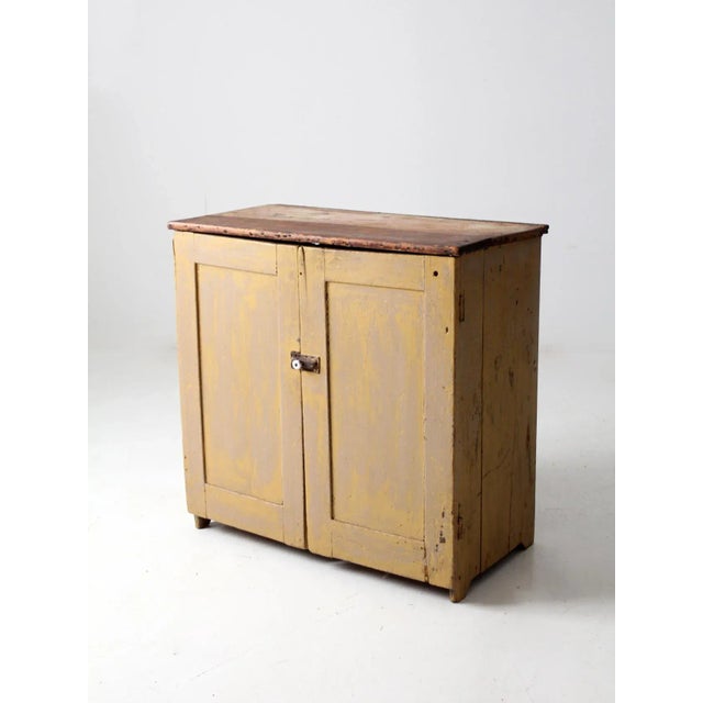 This is an antique cupboard cabinet. This fine example of a primitive cabinet features double doors with a ceramic knob...