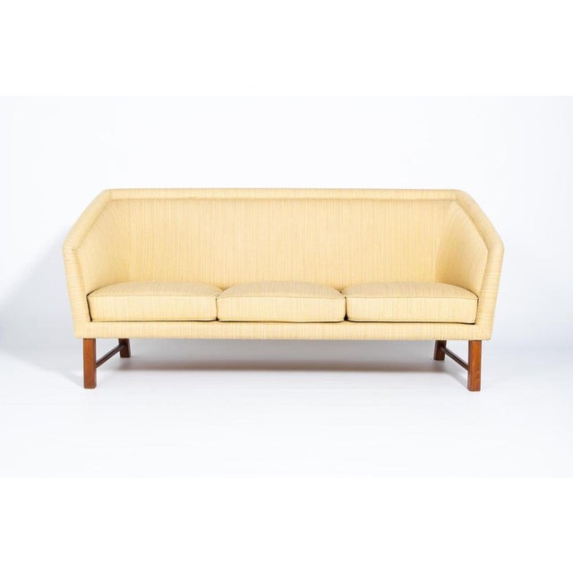 This beautiful shape mid-century sofa from 1950s is upholstered in light mustard wool fabric and has a solid stained wood...