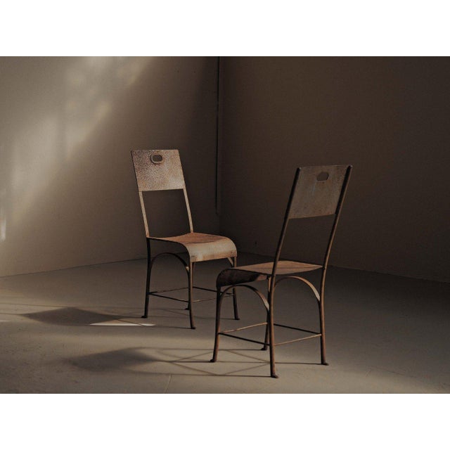Pair of metal chairs dating from around 1920. The frames are made from curved steel rods, forming simple arches beneath...