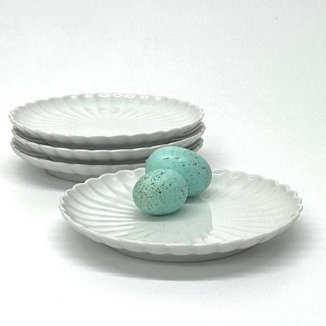 White plates, group of 4. This is a delicate set of white porcelain scalloped-edge chrysanthemum side plates from the...