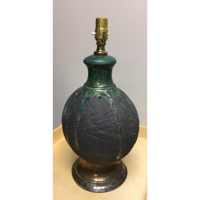 Mid century modern green raku pottery table lamp. Features dark green and gun metal textured round body with tapered neck....
