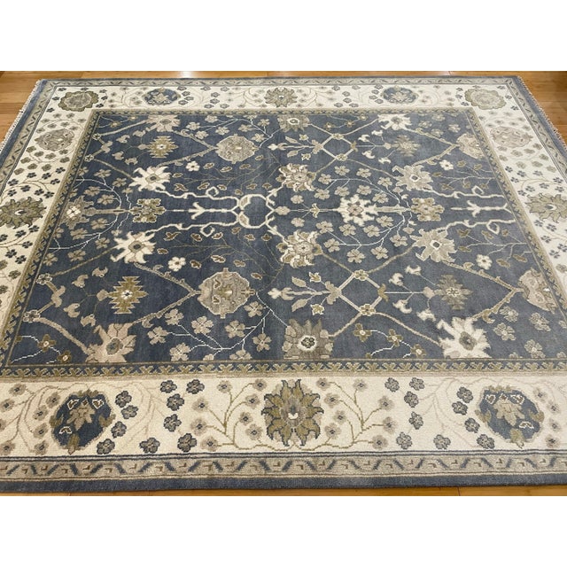 This is a Pakistani Ziegler Kafkaz rug, featuring a deep slate blue field with elegant floral and vine motifs in soft...