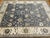 This is a Pakistani Ziegler Kafkaz rug, featuring a deep slate blue field with elegant floral and vine motifs in soft...