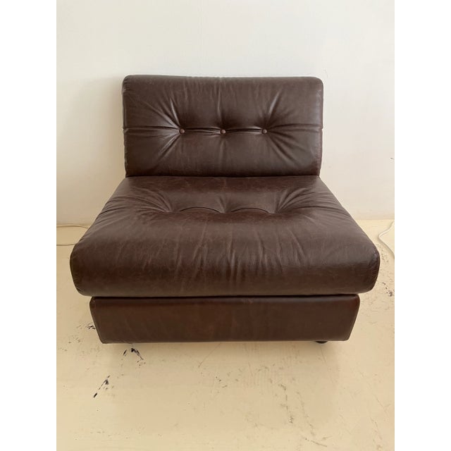 Armchair with brown leather upholstery and fiberglass supporting shell,