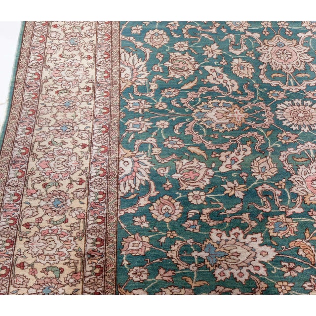 A hand-knotted wool antique Persian Tabriz rug dating back to 1920. The main field features a grid of enlarged palmettes,...