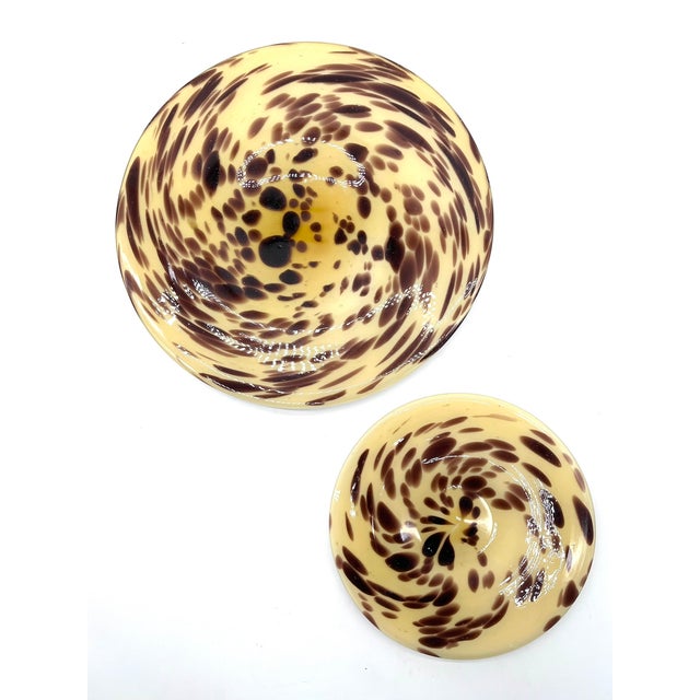 Decorative set of two bowls with a striking tortoiseshell pattern in warm amber, yellow, and brown tones on a white opal...