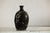 A dark brown late Qing Dynasty ceramic wine jug with hand-painted calligraphy and a timeworn patina. This antique vessel...