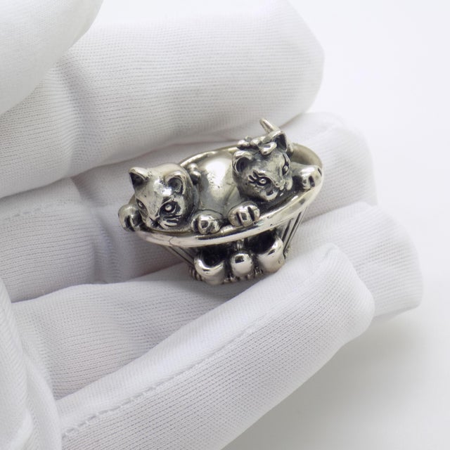 This vintage silver animal sculpture depicts two kittens resting inside a woven basket, crafted as a desktop accent,...