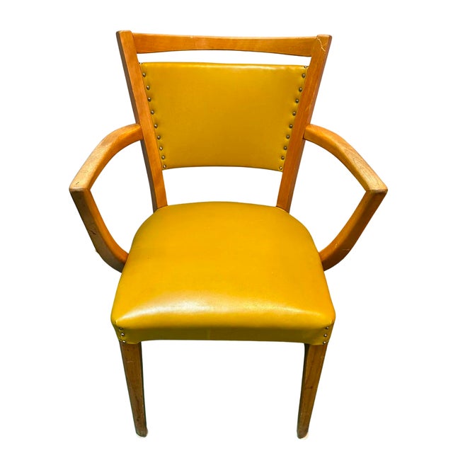 Vintage Henderson armchair featuring a warm wood frame and mustard yellow vinyl upholstery. The chair has a distinctive...