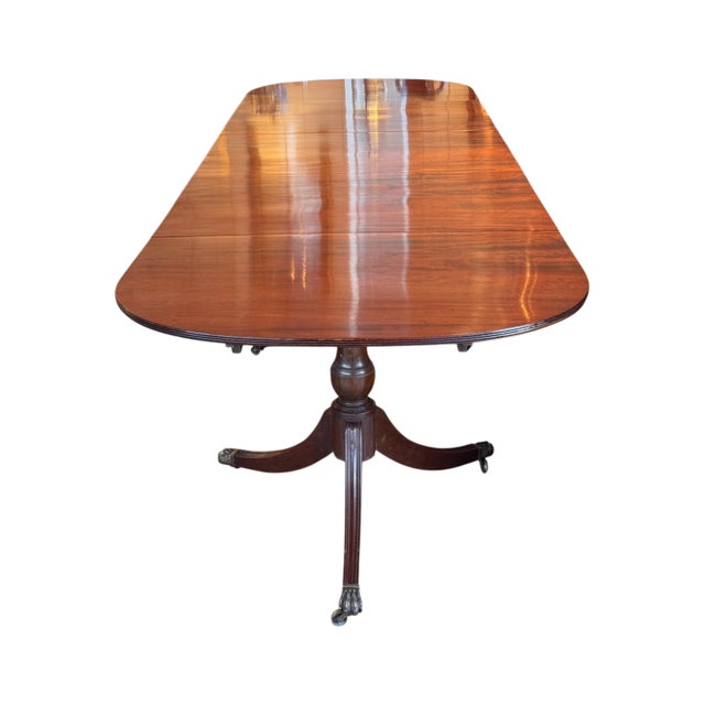 A 19th century mahogany triple pedestal dining table with an elongated rectangular top and rounded ends, constructed to...