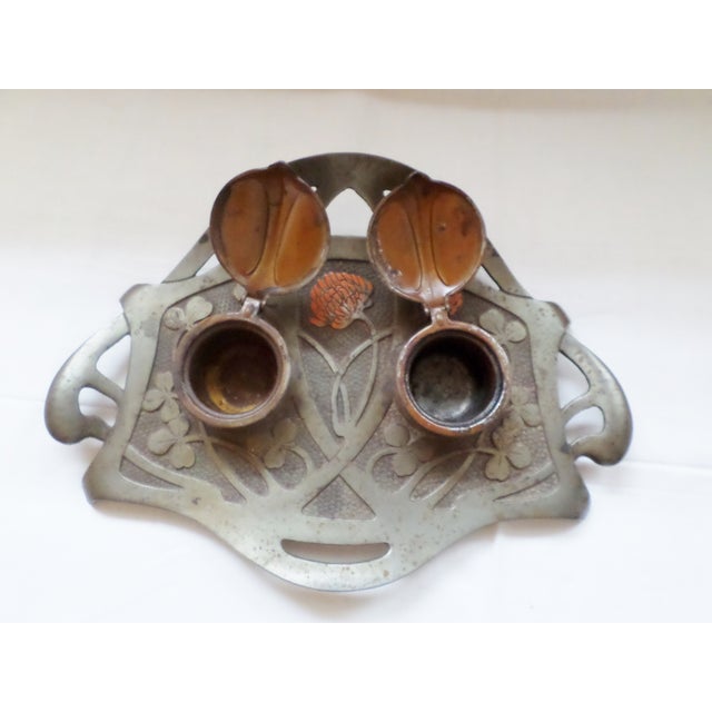 This is a Antique Art Nouveau Austria Geschutzt Double Inkwell with Pen Holder and has a Ornate Flower Design. It measures...