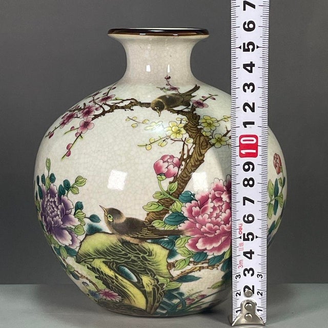 A beautiful Chinese porcelain vase featuring a creamy white Ge-type crackle glaze background. The vase is finely hand-...