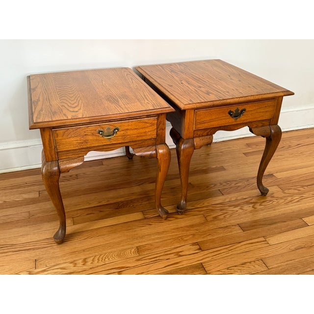 Pair of Lenoir House by Broyhill solid oak Queen Anne side end tables. They each have a drawer, pad foot, and original...