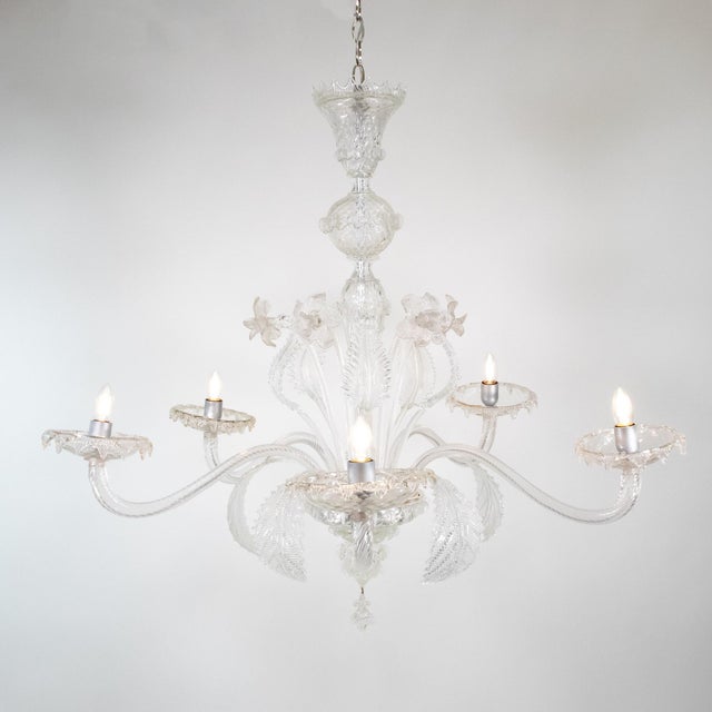 This handcrafted Cristallo Murano chandelier has five undulating scroll arms and features a bulbous center column with...