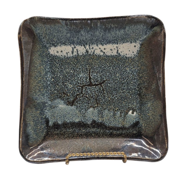 Glazed in ash and smoke, this square plate holds the echo of fire. Its corners rise gently—like a breath, or a...