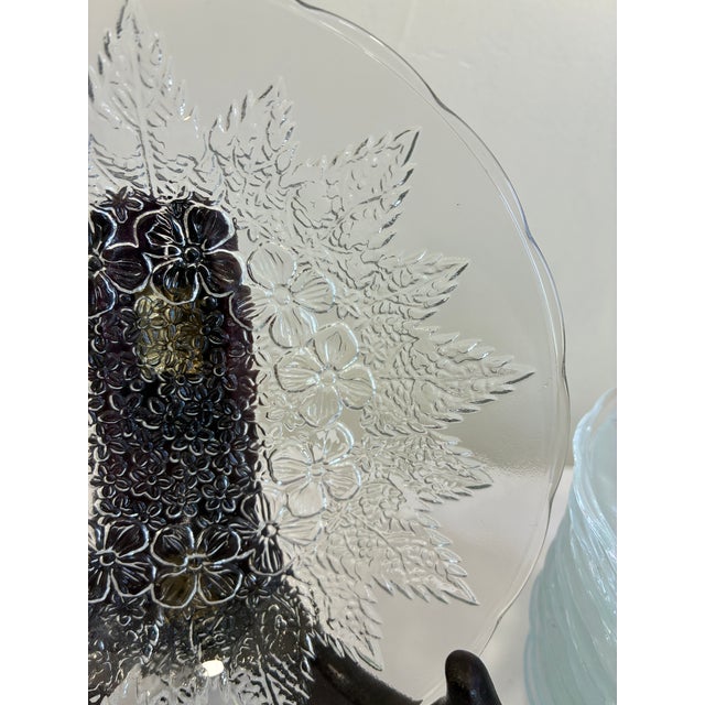 Set of 11 pressed glass plates made by KIG Indonesia. These clear glass dishes feature a detailed floral and leaf pattern...