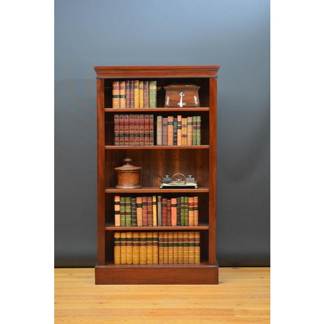 Late Victorian open bookcase of tall and narrow design in attractive figured mahogany, having oversailing top above four...