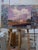 This oil painting depicts a desolate landscape featuring an abandoned structure, framed by a dramatic sky filled with...