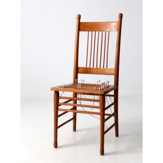 An early 20th-century spindle back chair that reads as a sculptural art object. The tall arched crest and slender spindles...