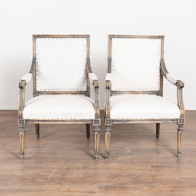 Pair of 19th century Swedish Gustavian armchairs crafted in pine. The chairs feature carved fluted detailing throughout,...