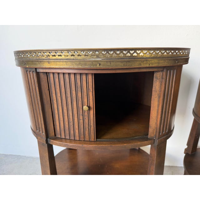 Elegant pair of vintage French Regency style nightstands by Baker Furniture, crafted in rich walnut-toned wood and topped...