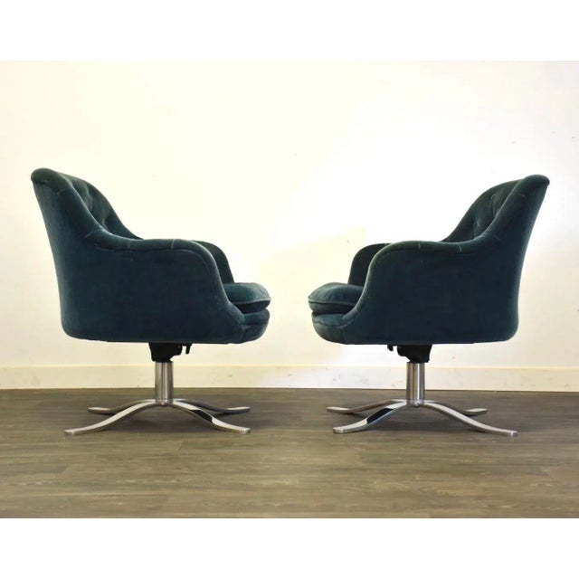A pair of mid century modern chrome star swivel base lounge chairs designed by Nico Zographos. Upholstered in a blue green...