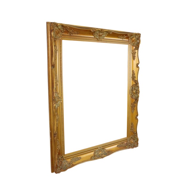 Large gold-colored pine frame, entirely in classic Baroque style, decorated with acanthus leaves, flowers, and a ribbon...
