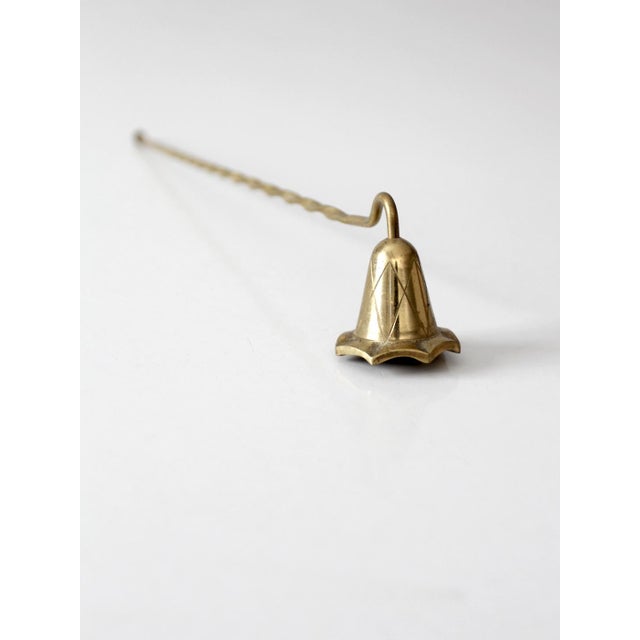 Vintage brass candle snuffer with a long twisted handle and engraved bell-shaped snuffer, finished with a delicate...