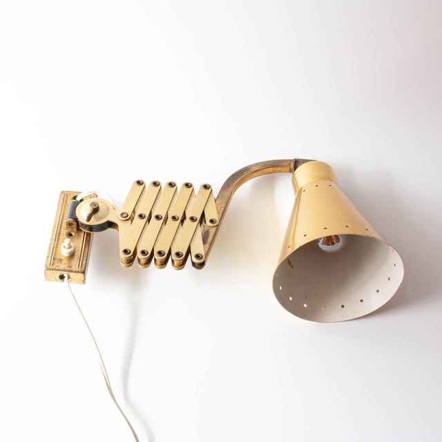 This vintage brass scissors wall lamp was designed by Karl Lang for SIS Leuchten, Germany, is a striking blend of...