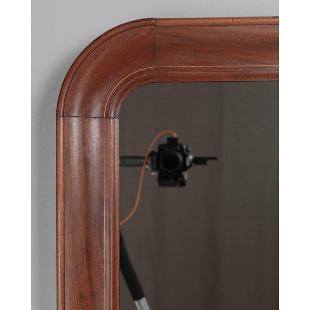 A French Louis Philippe style mirror with solid mahogany frame, curved top corners and fine inlaid detail. in good...
