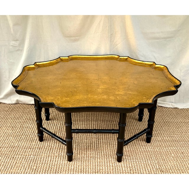 A Kittinger octagonal gold leaf coffee table on an ebonized faux bamboo base. Manufactured by the Kittinger Furniture...