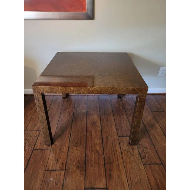 Large square Parsons-style side table in the manner of Milo Baughman, finished in a striking mottled copper-brown burl-...
