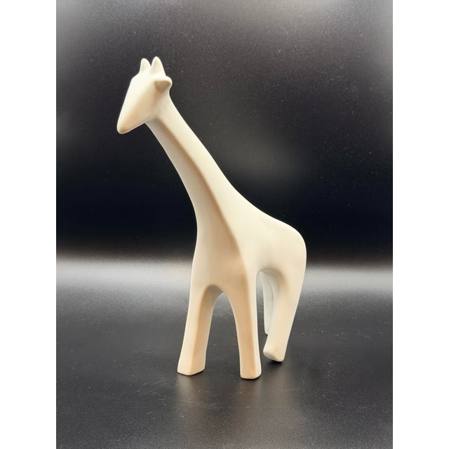 A striking minimalist giraffe sculpture defined by its elongated neck, clean lines, and soft matte white finish. This...